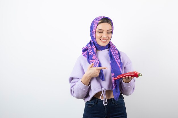 jovem mulher com um lenço apontando para uma pimenta vermelha.