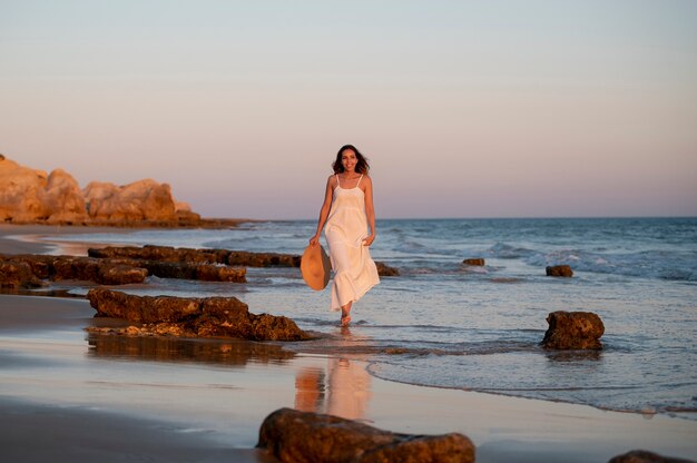 Jovem mulher com um vestido branco junto ao mar