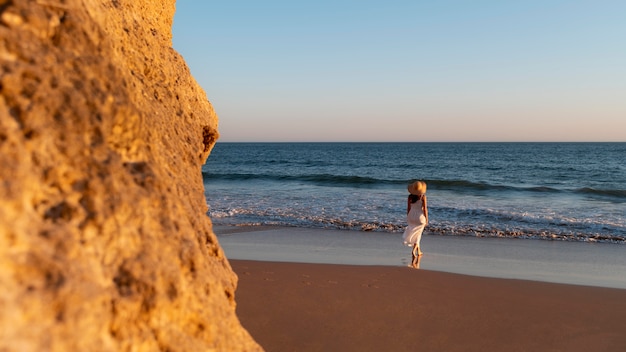 Jovem mulher com um vestido branco junto ao mar