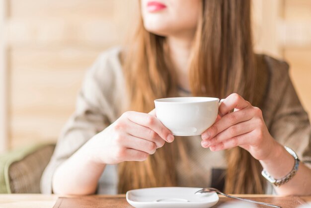 Jovem mulher com uma xícara de chá em suas mãos