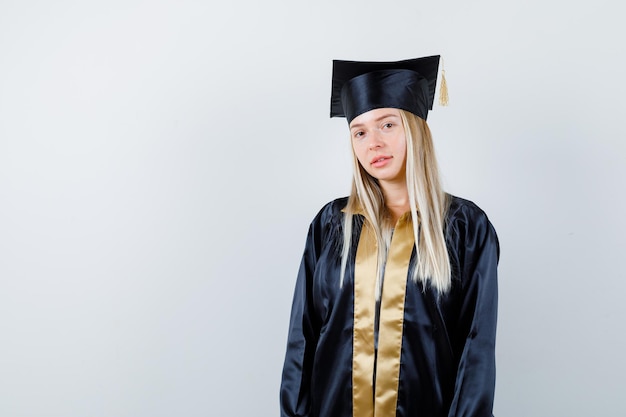 Jovem mulher com uniforme de pós-graduação, olhando para a câmera e parecendo sensata