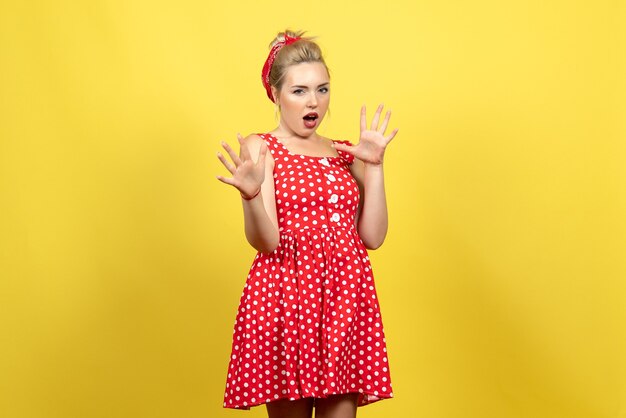 jovem mulher com vestido de bolinhas vermelhas apenas parada no amarelo