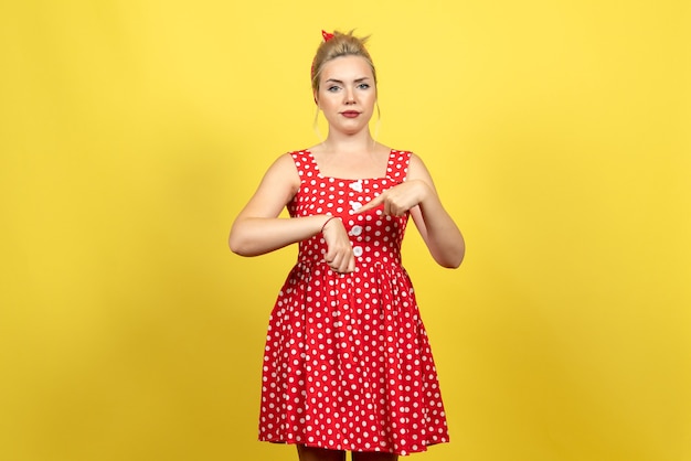 jovem mulher com vestido de bolinhas vermelhas mostrando o pulso amarelo