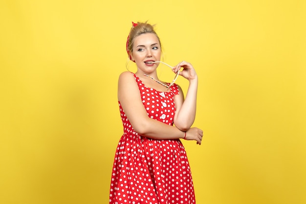 Foto grátis jovem mulher com vestido de bolinhas vermelhas posando com óculos de sol amarelo