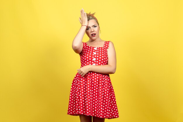 jovem mulher com vestido de bolinhas vermelhas, posando em amarelo claro