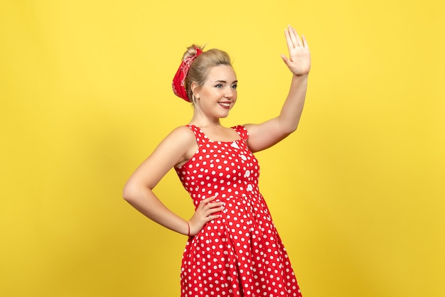 Foto grátis jovem mulher com vestido de bolinhas vermelhas, posando em amarelo