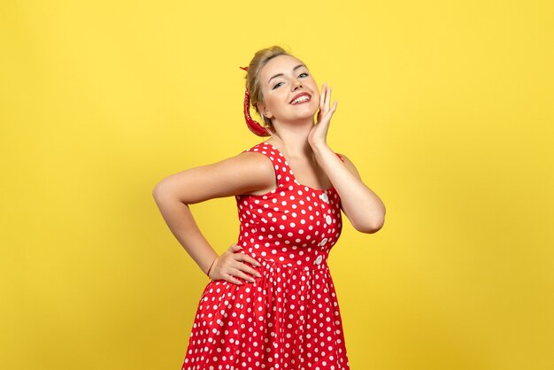 jovem mulher com vestido de bolinhas vermelhas, posando em amarelo