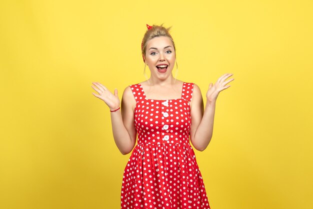 jovem mulher com vestido de bolinhas vermelhas, posando em amarelo