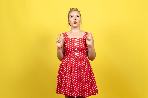 jovem mulher com vestido de bolinhas vermelhas, posando em amarelo