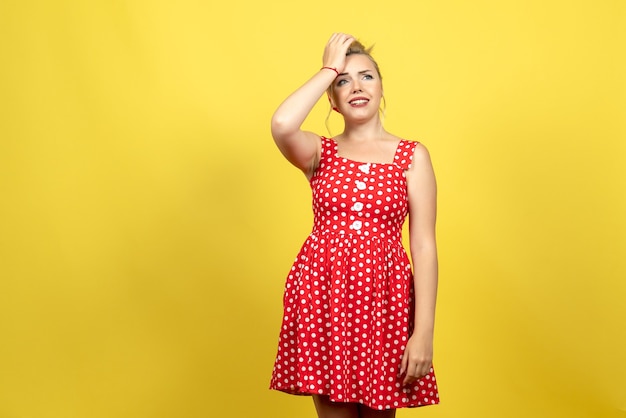 Foto grátis jovem mulher com vestido de bolinhas vermelhas, posando em amarelo