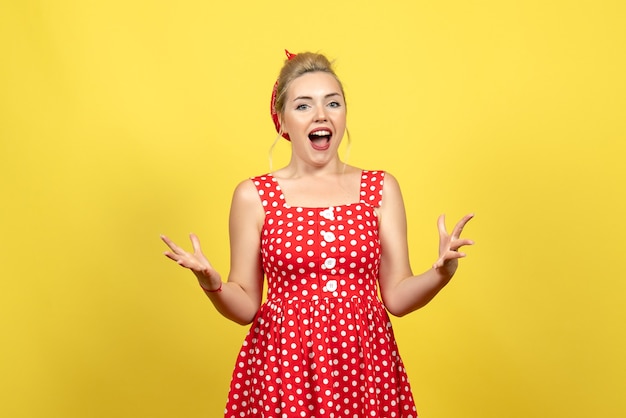 jovem mulher com vestido de bolinhas vermelhas, posando em amarelo