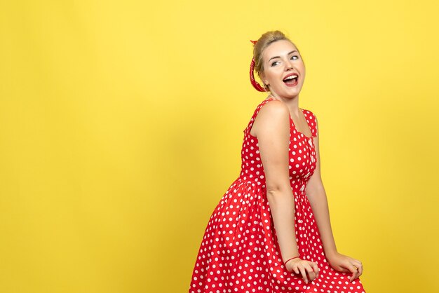 jovem mulher com vestido de bolinhas vermelhas, posando em amarelo