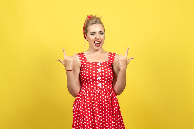 jovem mulher com vestido de bolinhas vermelhas posando emocionalmente em amarelo