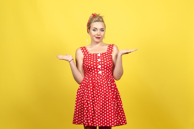 jovem mulher com vestido de bolinhas vermelhas sobre amarelo