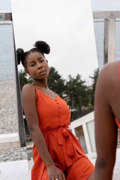 Jovem mulher com vestido vermelho posando ao ar livre com espelho