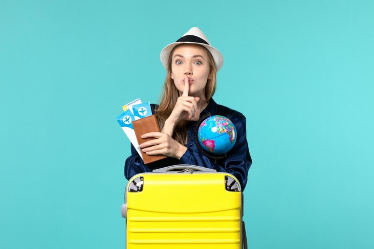 Foto grátis jovem mulher com vista frontal segurando bilhetes e um globo na viagem de viagem de férias de avião de fundo azul
