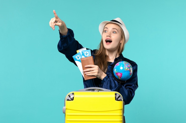 Foto grátis jovem mulher com vista frontal segurando bilhetes e um globo na viagem de viagem de férias de avião de fundo azul