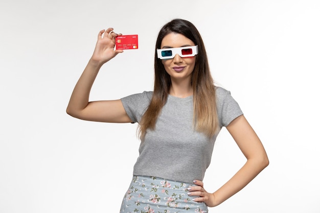 Jovem mulher com vista frontal segurando o cartão do banco em d óculos de sol na superfície branca