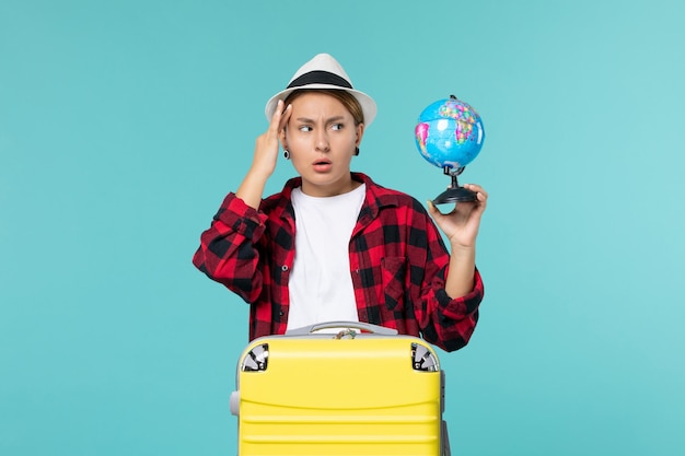 Jovem mulher com vista frontal segurando o globo e se preparando para uma viagem no espaço azul claro