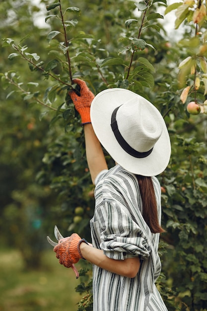 Jovem mulher cuidando das plantas. morena com um chapéu e luvas. mulher usa aveeuncator.