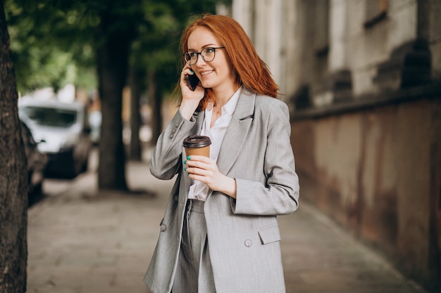 Jovem mulher de negócios ruiva usando o telefone