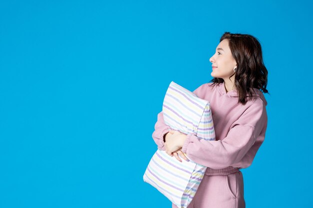 Jovem mulher de pijama rosa com almofada azul