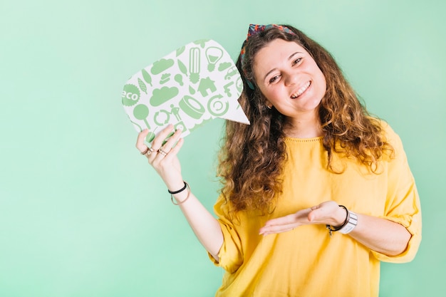 Foto grátis jovem mulher de sorriso que mantém a bolha do discurso contra o fundo pastel