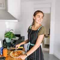 Foto grátis jovem mulher de sorriso que prepara a massa na cozinha