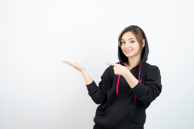 Jovem mulher desportiva de pé e apontando para a palma da mão aberta. Foto de alta qualidade