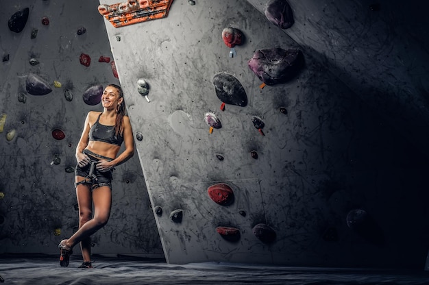 Jovem mulher desportiva escalando pedregulho artificial dentro de casa.