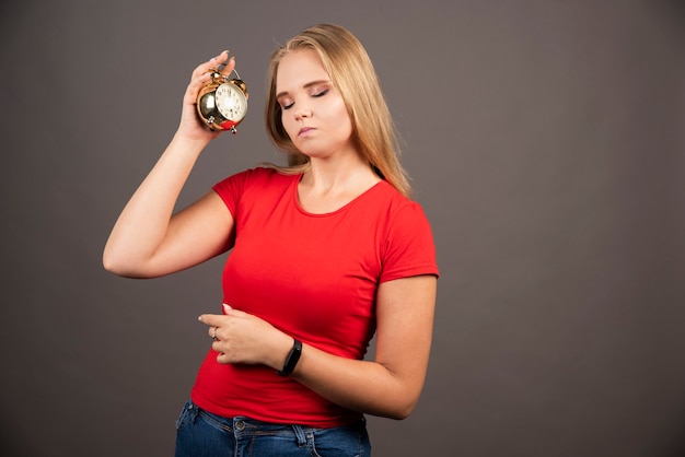 Foto grátis jovem mulher dormindo, segurando um pequeno relógio.