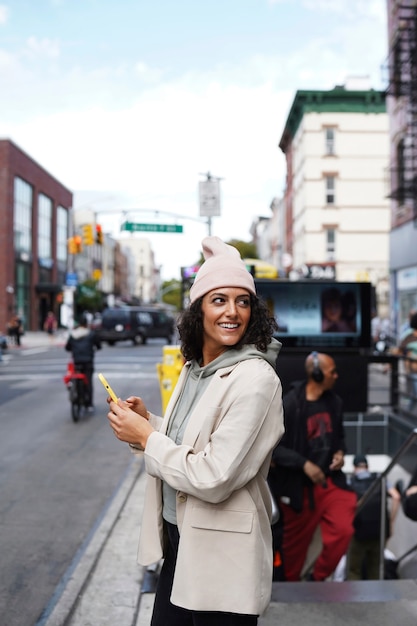 Jovem mulher elegante na cidade usando smartphone para exploração