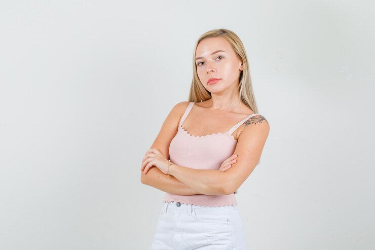 Foto grátis jovem mulher em pé com os braços cruzados em camiseta, minissaia e parecendo confiante