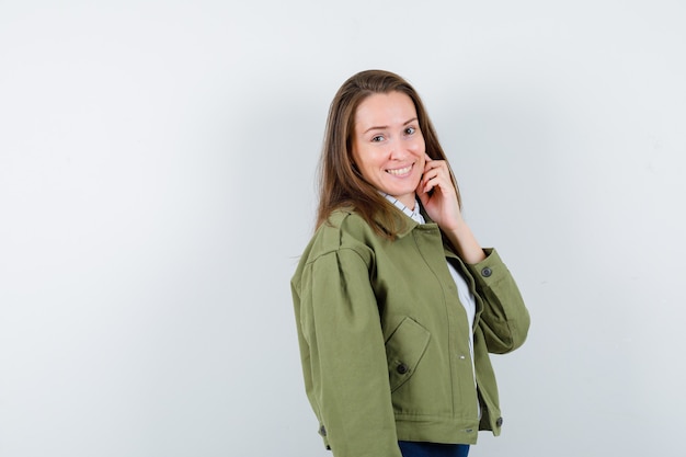 Jovem mulher em pé enquanto posava em uma camisa e está encantadora. vista frontal.