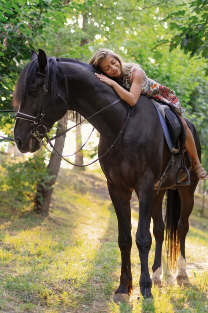 Jovem mulher em um vestido colorido brilhante, montando um cavalo preto