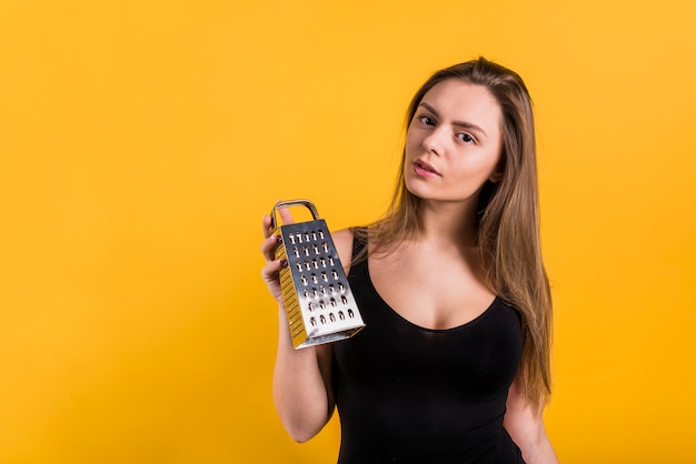 Jovem mulher encantadora mostrando ralador