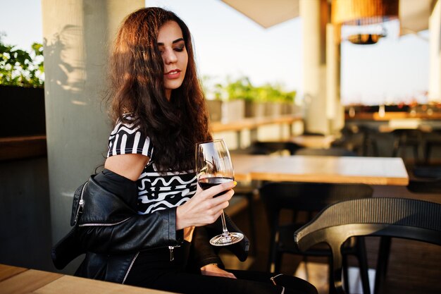 Jovem mulher encaracolada desfrutando de seu vinho em um bar