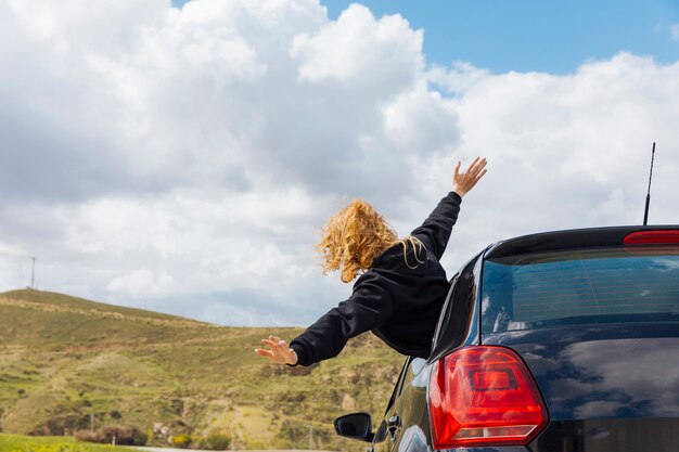 Jovem mulher encaracolada, inclinando-se da janela do carro