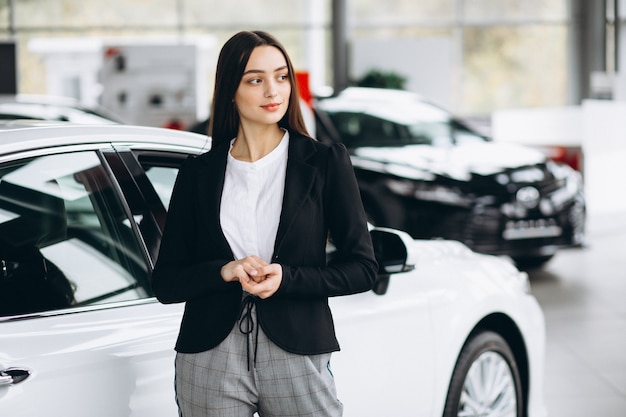 Jovem mulher escolhendo um carro em uma sala de exposições