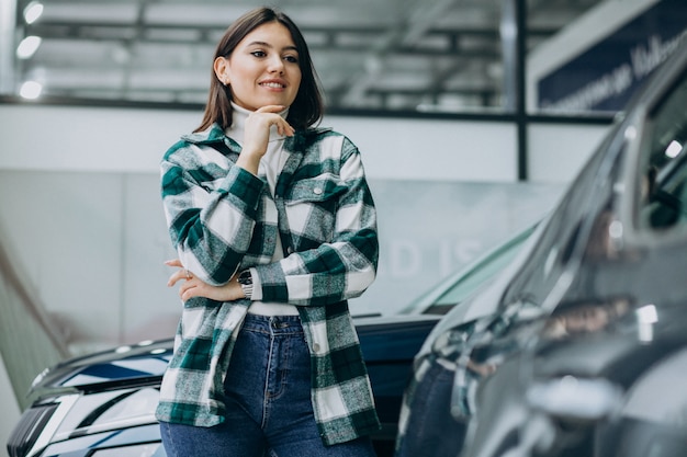 Jovem mulher escolhendo um carro em uma sala de exposições