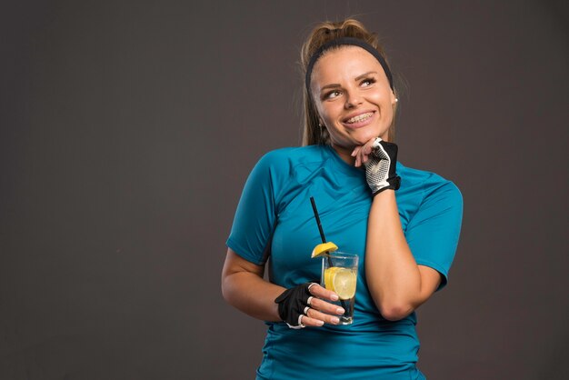 Jovem mulher esportiva está feliz após o treino e beber água com limão.