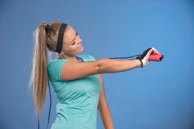 Foto grátis jovem mulher esportiva segurando cordas de pular e esticando o ombro.