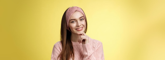 Foto grátis jovem mulher europeia feliz em suéter de faixa de tricô inclinando a cabeça tocando o queixo e sorrindo tolo