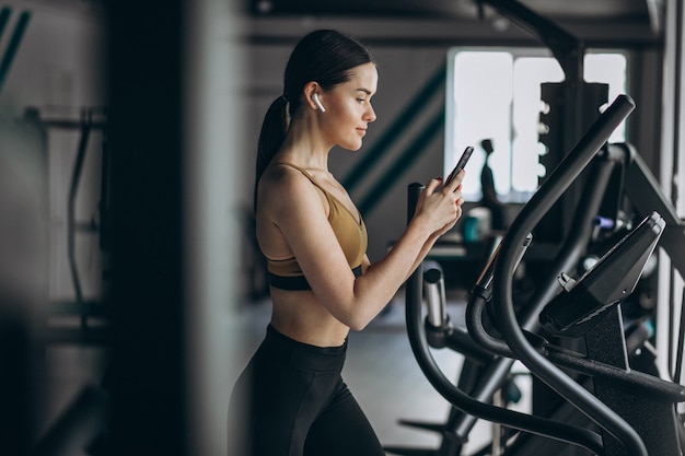 Jovem mulher exercitando na academia elíptica