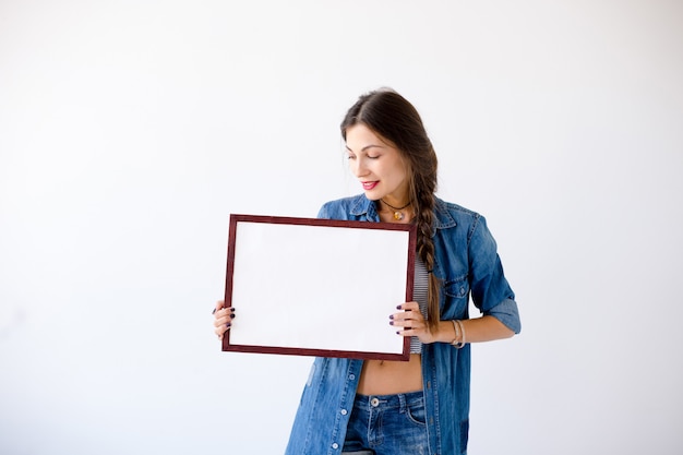 Foto grátis jovem mulher exibindo um cartaz ou cartaz branco em branco