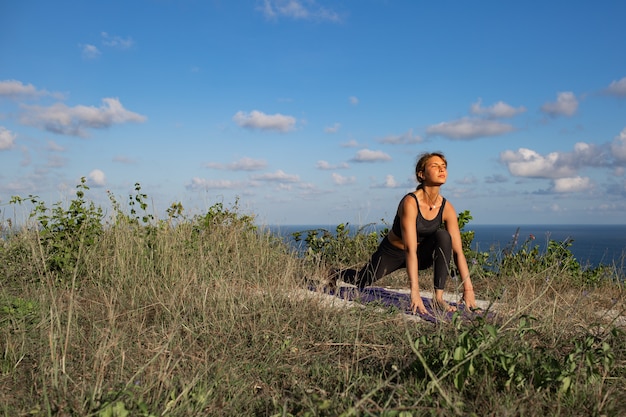 Jovem mulher fazendo ioga ao ar livre com incrível vista traseira. Bali. Indonésia.