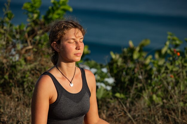 Jovem mulher fazendo ioga ao ar livre com incrível vista traseira. Bali. Indonésia.