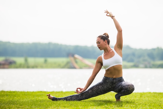 Jovem mulher fazendo pose de ioga no parque pela manhã com luz do sol
