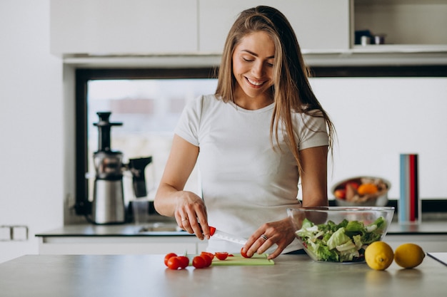 Foto grátis jovem mulher fazendo salada na cozinha
