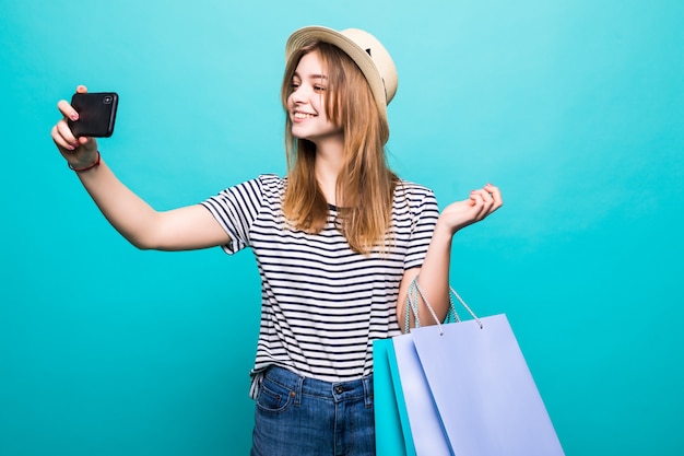 Jovem mulher fazendo uma selfie em seu smartphone sentado com sacos coloridos para fazer compras